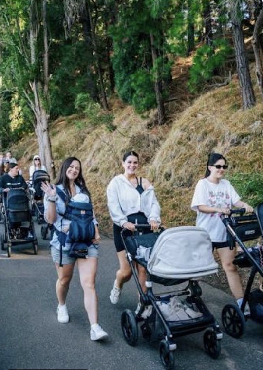 Women walking together with prams on a leafy path